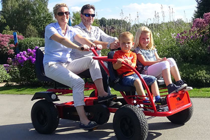 Family of 4 riding dino kart through the park
