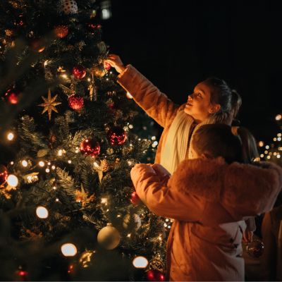 two girls putting decorations on a christmas tree