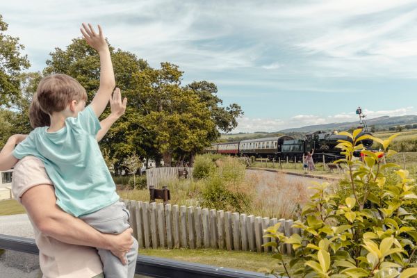 Steam train passing through Blue Anchor with children waving