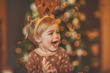 Infant clapping hands with reindeer ears 