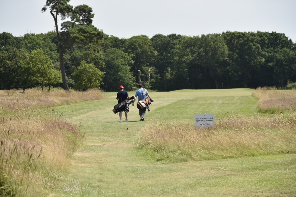 People walking with golf clubs on the golf field